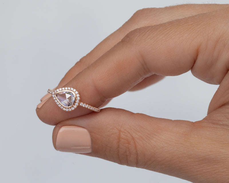 0.60 Carat  east west rose cut pear diamond  in 14k rose gold blair setting with halo and pavé diamonds held by fingers